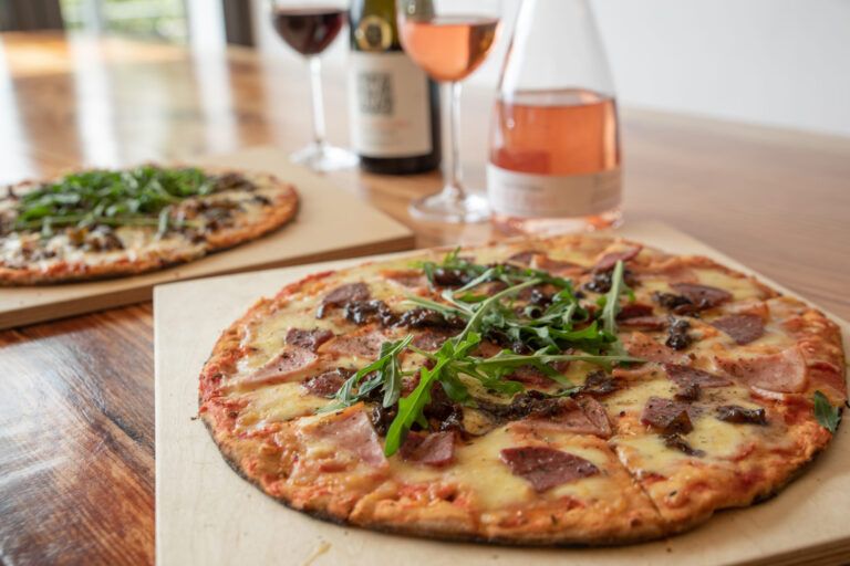 two pizzas on table with wine in glass in tasting room