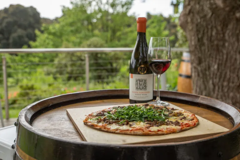 experiences at Elgin Valley depicted by a pizza and wine with wine glass on wine barrel